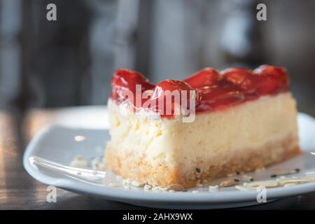 Libre tranche gâteau au fromage aux fraises dessert gâteau de nourriture sur une plaque blanche à l'arrière-plan flou artistique cafe Banque D'Images