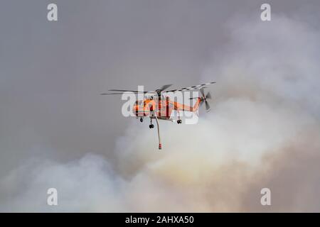 Erickson Air Crane N243AC (hélicoptère Sikorsky S-64) voler contre panaches de fumée pendant la lutte contre les feux de brousse dans la région de Victoria, en Australie. Banque D'Images