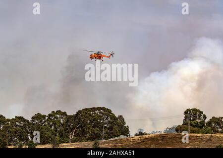 Erickson Air Crane N243AC (hélicoptère Sikorsky S-64) voler contre panaches de fumée pendant la lutte contre les feux de brousse dans la région de Victoria, en Australie. Banque D'Images