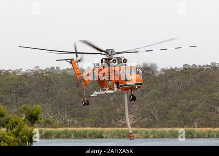 Erickson Air Crane hélicoptère décoller après le remplissage avec une charge d'eau pour combattre un incendie. Banque D'Images