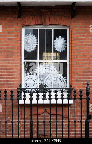 Décorations de Noël flocon de papier dans une fenêtre de la chambre. Chelsea, Londres, Angleterre Banque D'Images