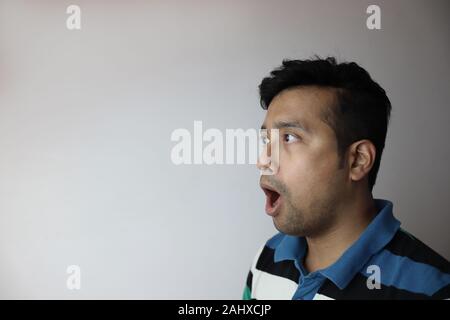 Coucou . côté gauche face à un homme asiatique avec expression étonné à la copie vers un espace avec fond gris Banque D'Images
