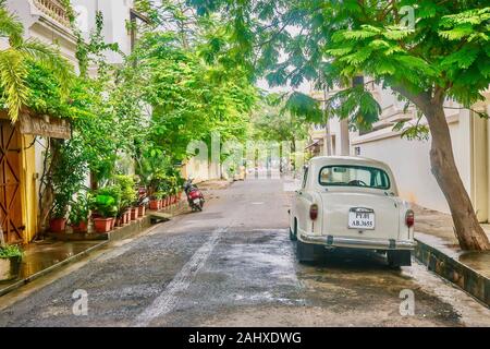 Pondichéry, Inde - le 9 décembre 2013. Un ambassadeur vintage beige voiture est garée dans une rue de la ville blanche domaine de l'ancienne ville coloniale française. Banque D'Images