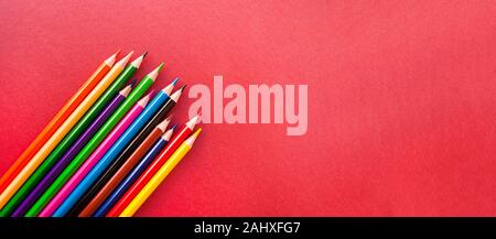 Crayons de couleur sur fond rouge avec copyspace. Bannière de l'école. Banque D'Images