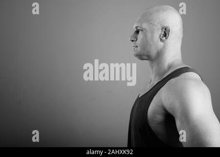 Bald man wearing tank top musclé contre l'arrière-plan gris Banque D'Images