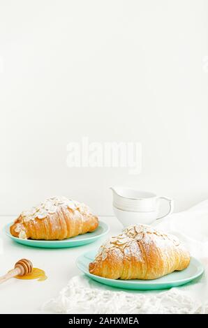 Les croissants aux amandes et flocons de sucre en poudre sur la plaque turquoise. L'espace de copie, à la verticale. Concept de petit-déjeuner Banque D'Images