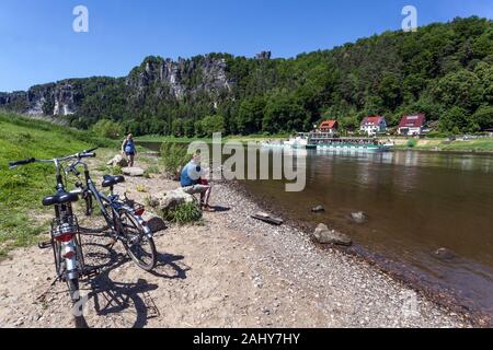 Les cyclistes s'arrêtent sur les rives de l'Elbe dans la vallée en contrebas des rochers de grès de l'Elbe Bastei, dans le parc national de la Suisse saxonne Allemagne Banque D'Images