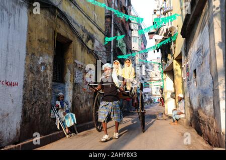 22.02.2011, Kolkata, Bengale occidental, Inde - un rickshaw puller prend deux filles à l'école dans son pousse-pousse en bois. Banque D'Images