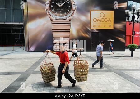 04.08.2012, Chongqing, Chine, Asie - Un portier, également appelé homme bang-bang, porte des paniers vides pour les marchandises suspendus à un mât de bambou. Banque D'Images