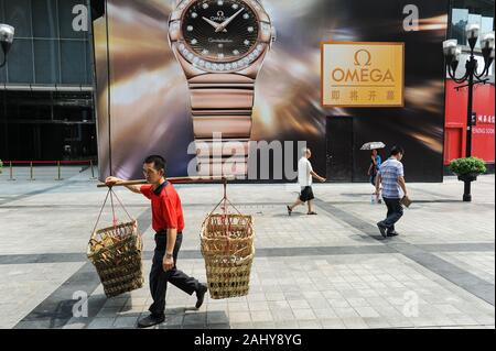 04.08.2012, Chongqing, Chine, Asie - Un portier, également appelé homme bang-bang, porte des paniers vides pour les marchandises suspendus à un mât de bambou. Banque D'Images