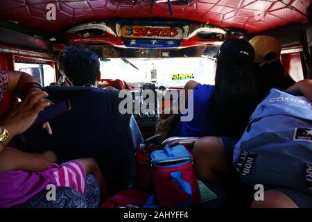 Antipolo City, Philippines - Le 27 décembre 2019 : Le pilote et les passagers à l'intérieur d'une jeep de passagers voyageant sur une journée ensoleillée. Banque D'Images