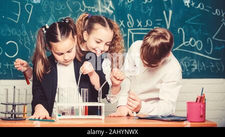 Des enfants heureux. Leçon de chimie. Les petits enfants l'apprentissage de la chimie. les étudiants en expériences en biologie avec microscope en laboratoire. L'enseignement de la chimie. Équipements en chimie. Belle journée dans le laboratoire. Banque D'Images