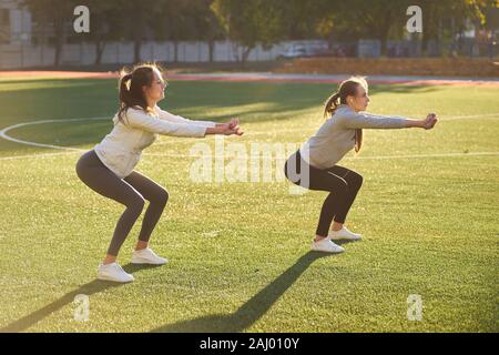 Deux jeunes filles faisant du sport la gymnastique le matin sur l'herbe verte. open air, Dawn, remise en forme, santé, sports. Banque D'Images