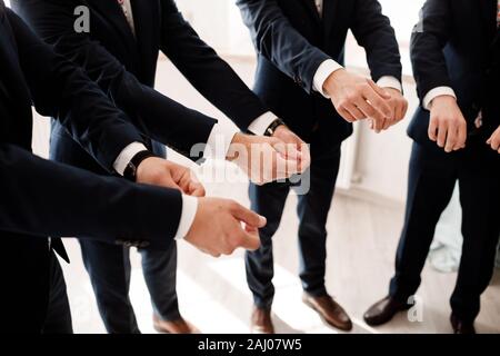 Le marié et ses amis dans l'élégant quartier de groomsman convient à la préparation avant le mariage dans la matinée , groupe émotionnel de l'ami. photo recadrée. Banque D'Images