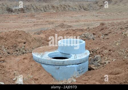 L'installation de puits d'égout en béton dans le sol à la construction site. L'utilisation d'anneaux en béton armé pour les puisards, fosses septiques de débordement Banque D'Images