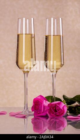 Deux verres de champagne et roses roses sur une table de réflexion Banque D'Images