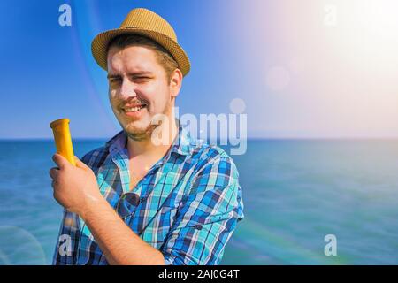 Guy mise sur crème solaire sur le visage. L'homme était tanné au soleil sur la mer, et il a utilisé l'écran solaire. Banque D'Images