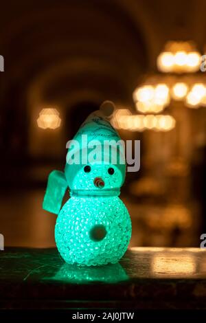 Petit bonhomme portant un foulard et un chapeau arc-en-ciel contre une lumière dorée bokeh en attente de l'époque de Noël et cadeaux Banque D'Images