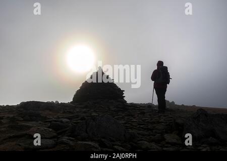 Walker sur le sommet du bord tombé comme les coups de soleil à travers les nuages, Coniston, Lake District, Cumbria, Royaume-Uni Banque D'Images