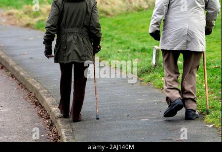 Couple de personnes âgées en hiver marchant avec des bâtons, Royaume-Uni Banque D'Images