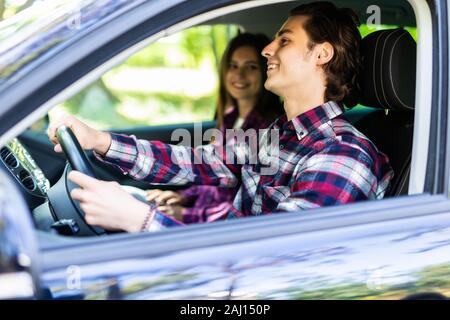 Couple romantique dans leur voiture partir en voyage. Jeune homme au volant de sa voiture avec un jour d'été. Banque D'Images