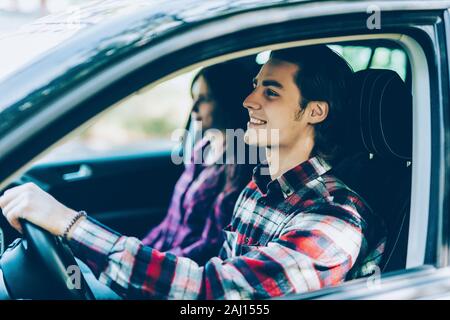 Couple romantique dans leur voiture partir en voyage. Jeune homme au volant de sa voiture avec un jour d'été. Banque D'Images