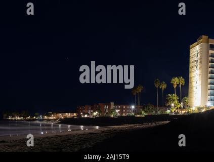 Hôtel de 11 étages éclairés par des lampes d'éclairage de nuit au-dessus des tours de condos et maisons qui bordent la promenade de la plage de Ventura riviera. Banque D'Images