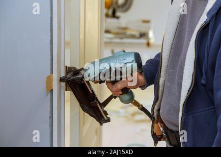 Carpenter en utilisant de l'air pistolet installation d'installer dans la nouvelle porte Banque D'Images