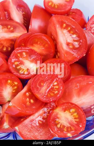 Assortiment de tranches de tomates dans un bol en verre bleu transparent. Banque D'Images