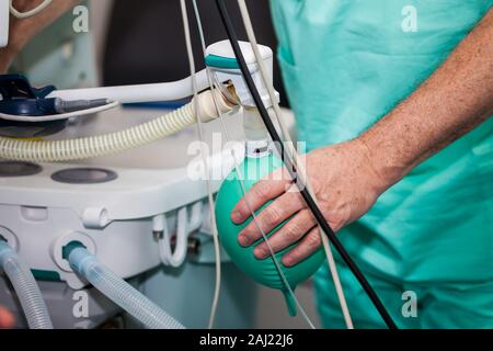 Close up d'un médecin part en appuyant sur le sac de réaspiration d'anesthésie chirurgicale alors que leur équipe se prépare pour la chirurgie des patients Banque D'Images
