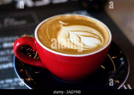 Caffee latte macchiato cappuccino au café rouge mug en chambre avec l'art de la mousse de lait Banque D'Images