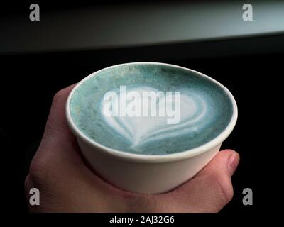La main d'une femme hplding eco friendly tasse de pois papillon latte avec belle forme coeur latte art, rafraîchissements Banque D'Images