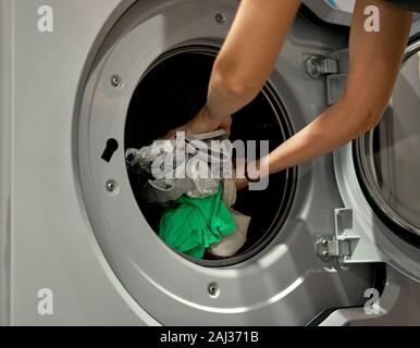 Girl met les choses dans la machine à laver Banque D'Images