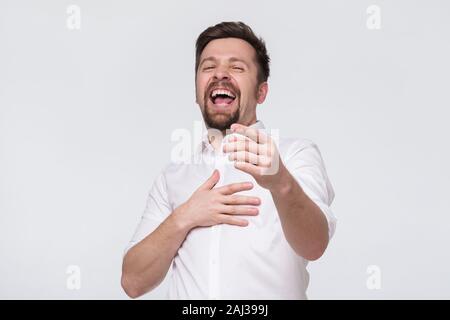 Couple d'âge mûr avec une barbe rire tenant son estomac et sur vous. Concept bonne blague. Banque D'Images