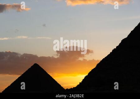 Coucher du soleil jaune vif derrière silhouette de Khafré et Menkaourê pyramides Banque D'Images