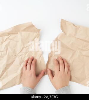 Deux mains de déchirer une feuille de papier kraft brun, vue du dessus Banque D'Images