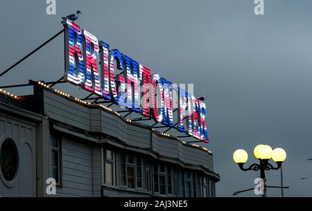 Brighton Palace Pier avec un panneau lumineux dans les couleurs Union Jack éclairé au crépuscule. La célèbre jetée est l'un des sites touristiques les plus visités du Royaume-Uni. Banque D'Images