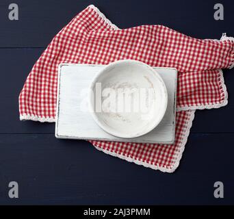 Cuisine coupe rectangulaire blanche et plaque ronde vide sur un fond en bois bleu, blanc rouge à côté d'une serviette textile, vue du dessus. Copy space Banque D'Images