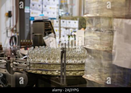 Les bouteilles de bière vides en verre blanc, au point sélective sur la courroie du convoyeur, machine système craft brewery microbrasserie usine entrepôt d'embouteillage Banque D'Images