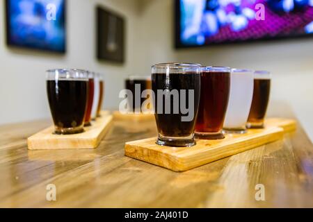 Vol de Plaisance de quatre bières différentes lunettes sur plateaux en bois au cours d'une dégustation, selective focus avec arrière-plan de la barre floue et copy space Banque D'Images