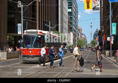 TORONTO, CANADA - 0627 2016 : les citadins de traverser la rue en face d'un vieux tramway sur King St Younge. intersection. Banque D'Images