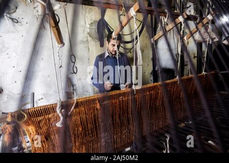 Un travailleur palestinien tisse des tapis sur un métier traditionnel en bois à une fabrique de tapis dans la ville de Gaza.Parler de vieille Gaza, et ce qui s'affiche sont des images d'argile poterie, verrerie colorée, mobilier en bambou et des métiers du bâti ancien tissage de tapis et tapis lumineux. Comme ces professions pourraient être en train de mourir dans le monde entier, le rythme de la baisse est trop rapide à Gaza que sur ses quelque 500 métiers, un seul est encore en activité. Banque D'Images