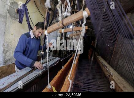 Un travailleur palestinien tisse des tapis sur un métier traditionnel en bois à une fabrique de tapis dans la ville de Gaza.Parler de vieille Gaza, et ce qui s'affiche sont des images d'argile poterie, verrerie colorée, mobilier en bambou et des métiers du bâti ancien tissage de tapis et tapis lumineux. Comme ces professions pourraient être en train de mourir dans le monde entier, le rythme de la baisse est trop rapide à Gaza que sur ses quelque 500 métiers, un seul est encore en activité. Banque D'Images