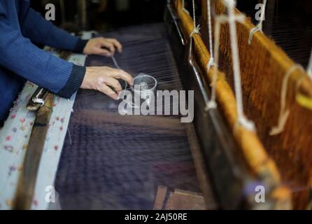 Un travailleur palestinien tisse des tapis sur un métier traditionnel en bois à une fabrique de tapis dans la ville de Gaza.Parler de vieille Gaza, et ce qui s'affiche sont des images d'argile poterie, verrerie colorée, mobilier en bambou et des métiers du bâti ancien tissage de tapis et tapis lumineux. Comme ces professions pourraient être en train de mourir dans le monde entier, le rythme de la baisse est trop rapide à Gaza que sur ses quelque 500 métiers, un seul est encore en activité. Banque D'Images