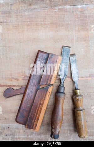 Vieux ciseaux à bois et autres outils à main posée à plat sur une surface rugueuse pièce de bois avec des touches de peinture et des rayures Banque D'Images