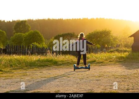 Girl riding a scooter sur une chaude soirée d'été. Banque D'Images