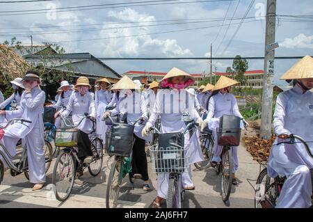 Delta du Mekong, Vietnam ; 10 octobre 2005. Les écolières à vélo à la maison de l'école portant l'uniforme traditionnel. Banque D'Images