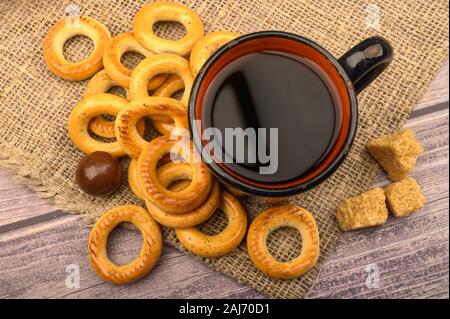 Bagels, petits chocolats, une tasse de thé et un tissu de fabrication locale sur un fond de bois close-up Banque D'Images