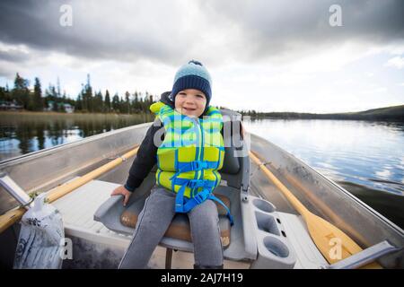 Jeune garçon assis dans un bateau en aluminium pendant la pêche. Banque D'Images