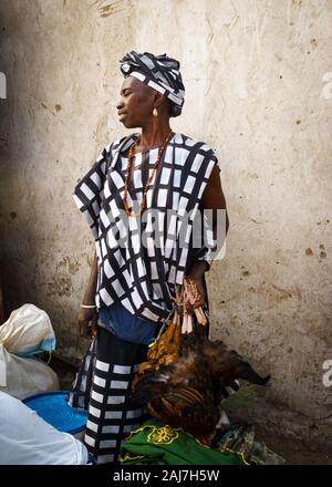 Fière femme africaine en tenue traditionnelle vente de poulets au marché au Sénégal, l'Afrique - Photo : Iris de Reus Banque D'Images